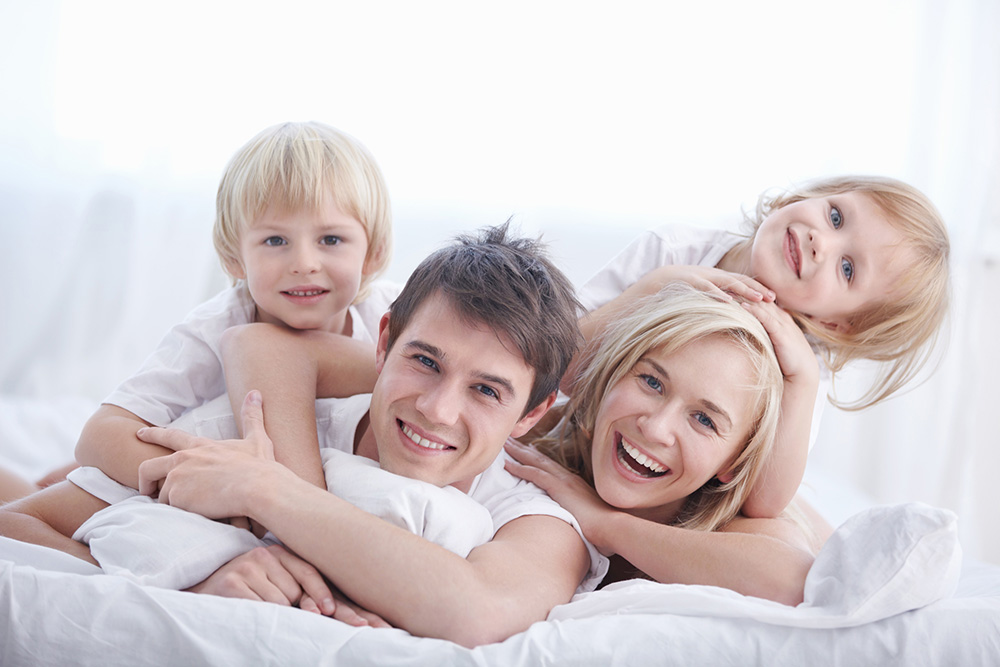 Happy family: mom, dad and two kids. Sheets safe, clean and white with Jade Disinfection services